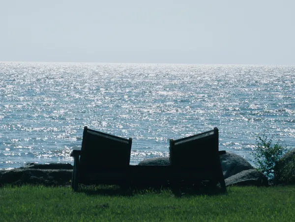 Two chairs beside a lakeside